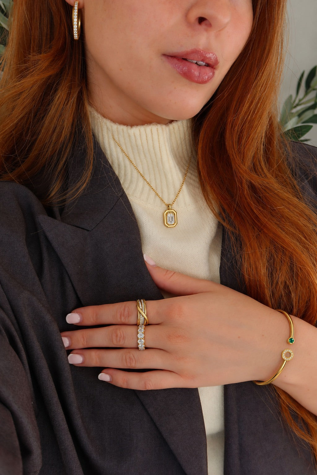 Gold jewelry styled with a cream knit and dark blazer